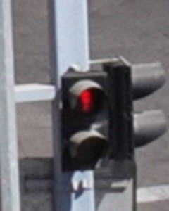 Close-up of the pedestrian signal head on the left pole, red lamp lit.