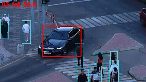 A car turns through the side-road crossing while pedestrians walk on it.